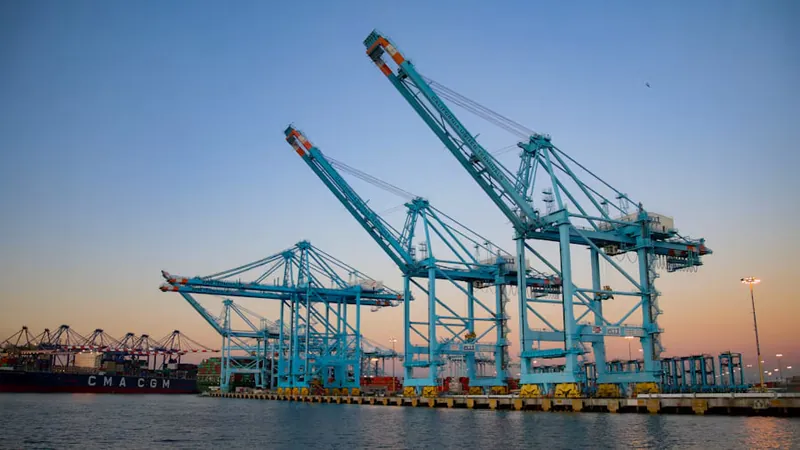 Grúas de un terminal de contenedores al atardecer, tema de importar desde Estados Unidos a Chile
